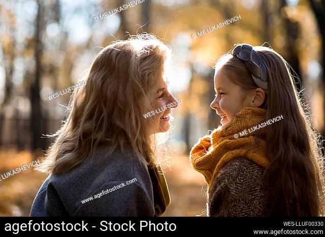 Blond woman smiling at daughter in public park