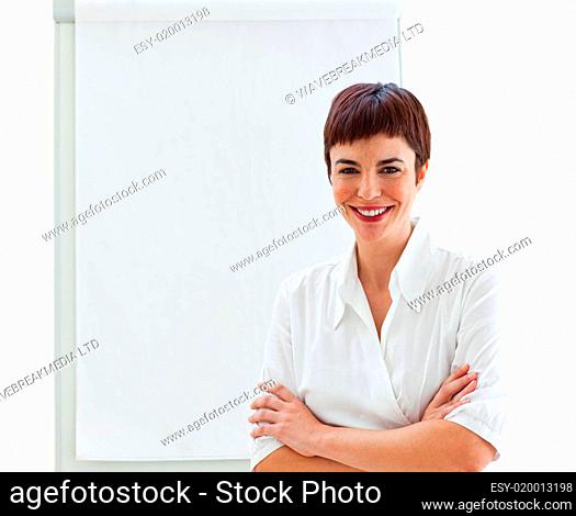 Young businesswoman with folded arms in front of a board