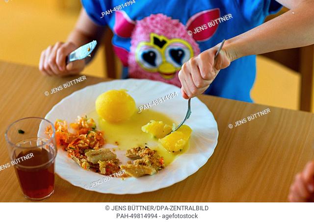 Nursery child Romina eats her lunch from her plate with a knife and fork at the integrated nursery 'Plappersnut' in Wismar, Germany, 19 June 2014