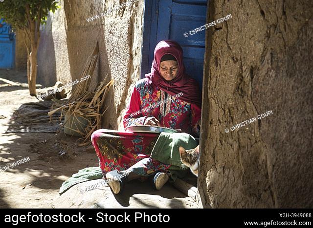 Woman sitting on her doorstep peeling garlic, village of Ramadi, west bank of the Nile south of Edfu, Egypt, North East Africa