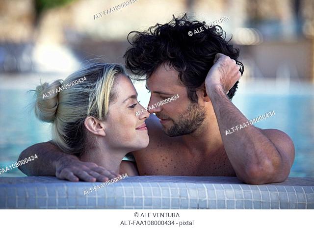 Affectionate couple relaxing together in pool
