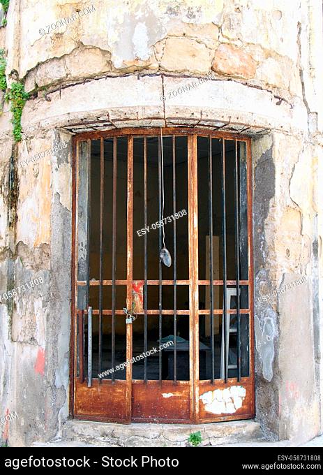rusted metal bars on the door of an old abandoned derelict building with cracked walls