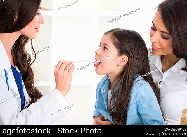 Little girl having throat examination by pediatrician at checkup in clinic