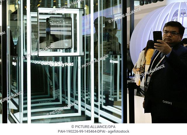 26 February 2019, Spain, Barcelona: Visitors photograph the new Samsung Galaxy Fold, a smartphone with a foldable display that stands in a glass showcase at the...