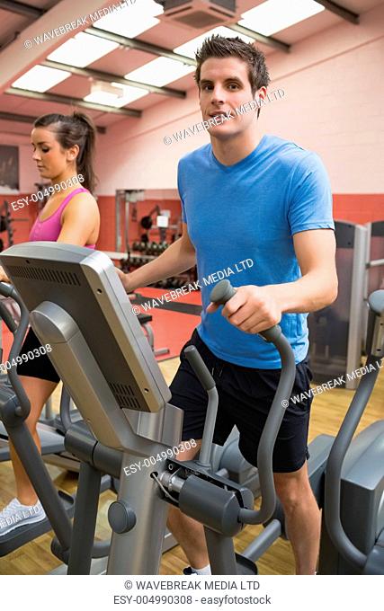 Man and woman stepping on a step machine in gym