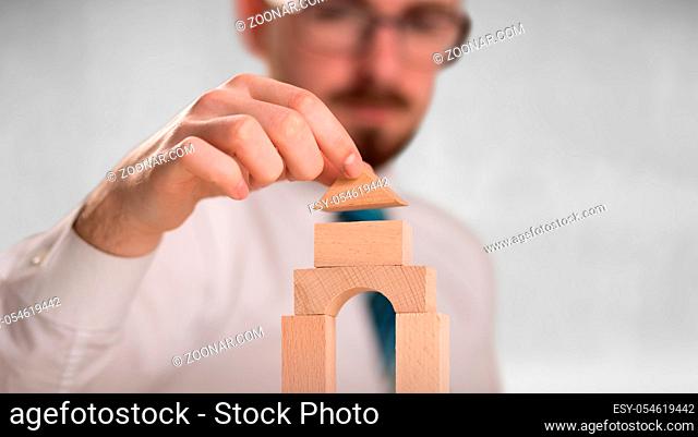 Young handsome businessman using wooden building blocks