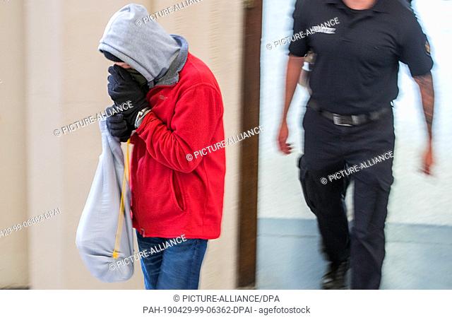 29 April 2019, Mecklenburg-Western Pomerania, Schwerin: The defendant is taken to the courtroom at the beginning of the trial for the murder of a pensioner in...