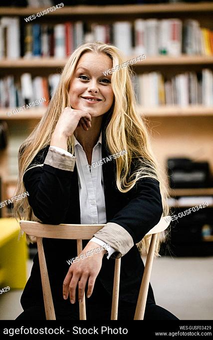 Portrait of a smiling young businesswoman sitting on a chair in loft office