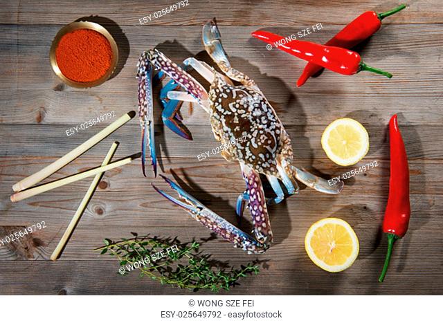 Above view raw blue crab and ingredients ready to cook, on wood background