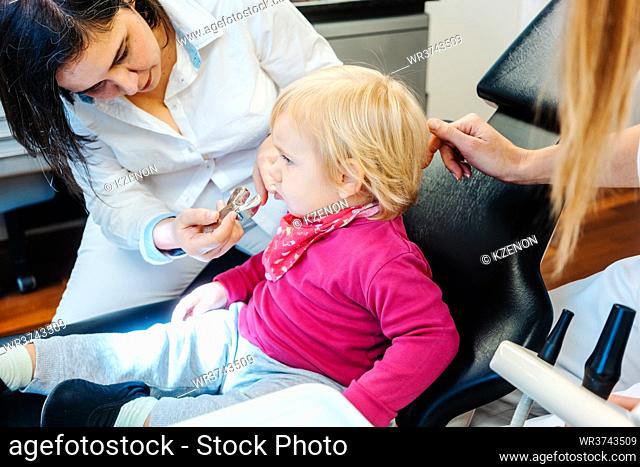 Friendly dentist checking teeth of a little child