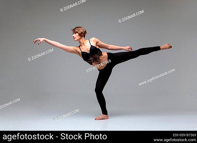 Beautiful young woman dancer making modern dancing elements. studio shot on grey background. copy space