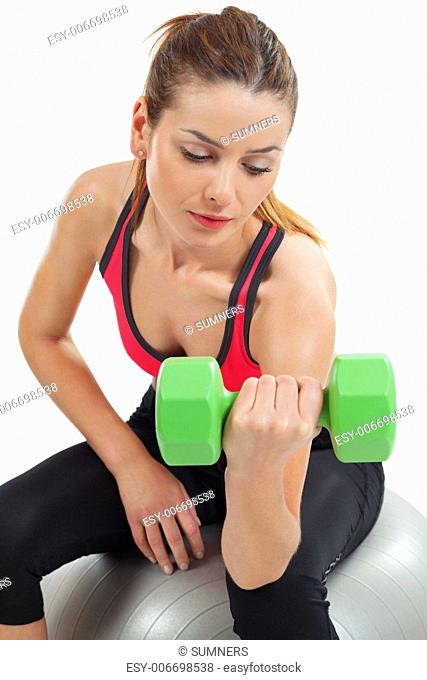 Photo of an attractive female doing dumbbell curls while sitting on an exercise ball