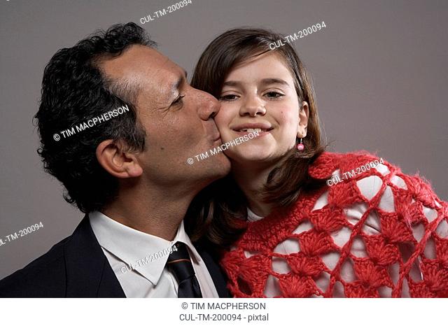 Father kissing daughter 9-11 on cheek