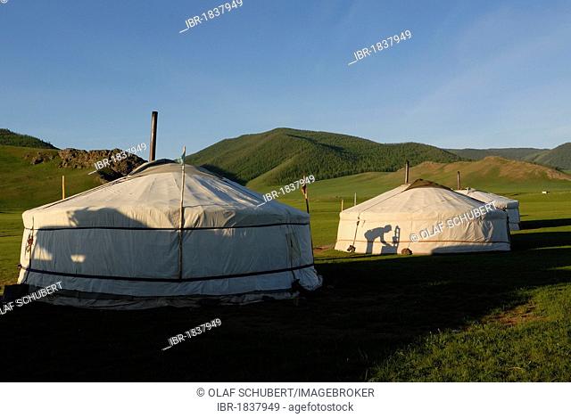 Yurt or ger camp with the shadow of a man washing himself, grassland at the Orkhon Waterfall in front of the mountains of Khangai Nuur National Park