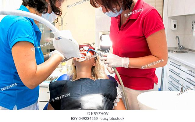 Dentist assistant holding salive ejector during teeth whitening procedure