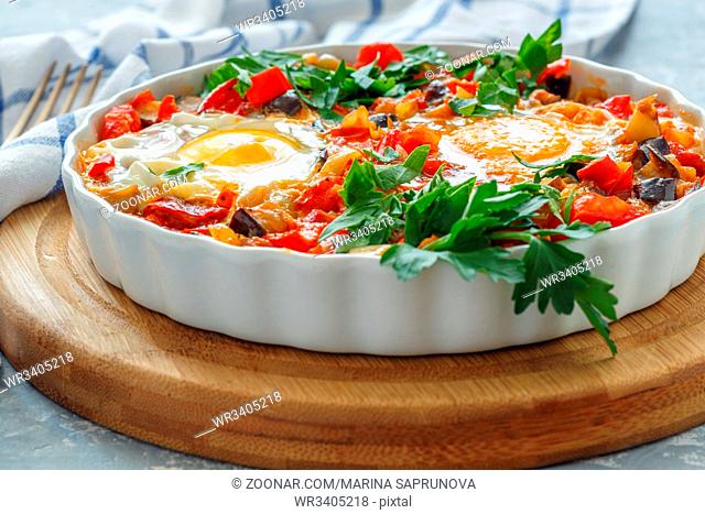 Traditional Israeli dish shakshuka with vegetables in a ceramic dish on the table close-up