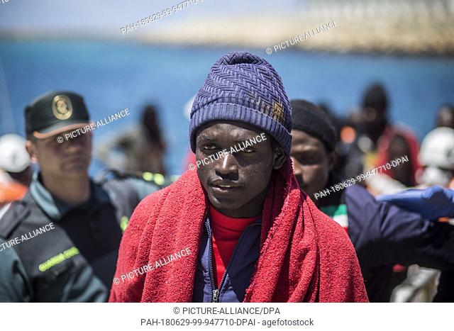 29 June 2018, Spain, Tarifa: An African migrant stands at the port of Tarifa covered in red blankets after being rescued from the Strait of Gibraltar
