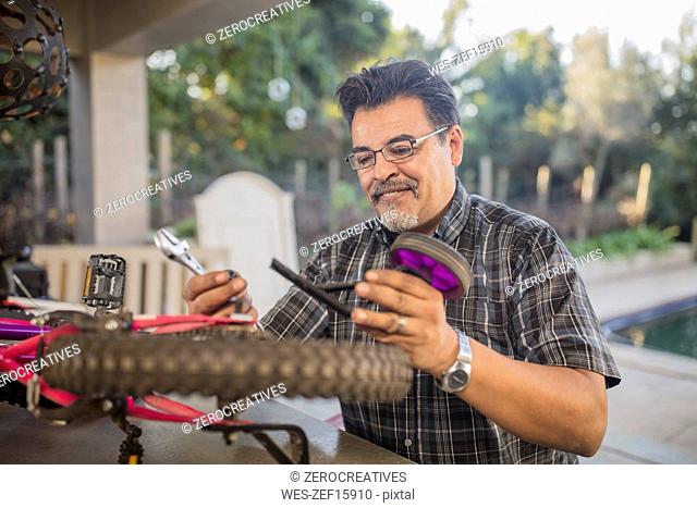 Man fixing stabilisers of children's bicycle