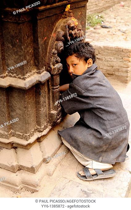 young nepalis boy praying at street shrine, the nepalis , life in kathmandu , kathmandu street life , nepal