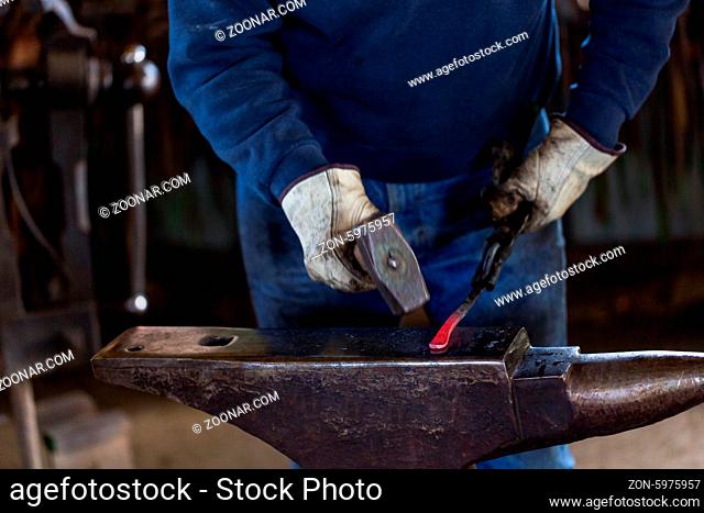 A blacksmith forging hot iron on the anvil