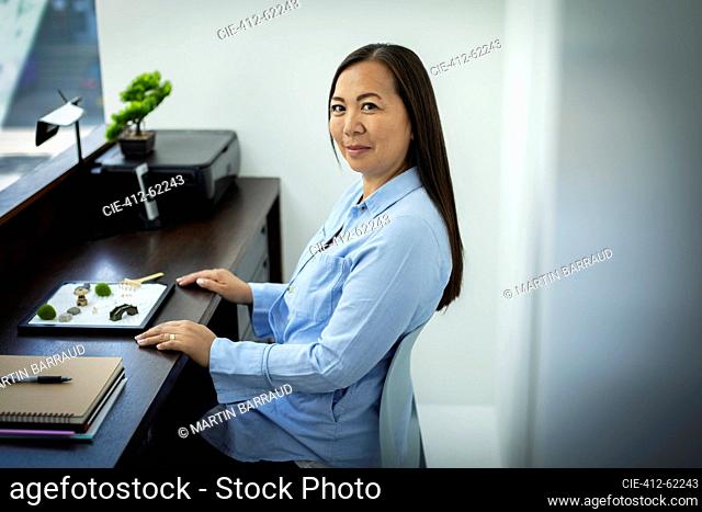 Portrait businesswoman with zen garden in office