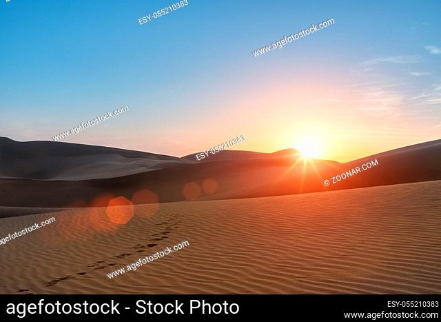 desert landscape in sunset, beautiful setting sun and footprints in the desert
