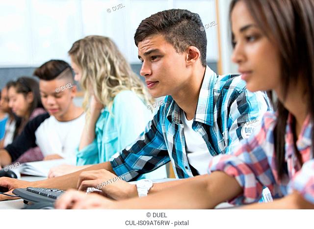 Row of teenage high school students concentrating in computer class