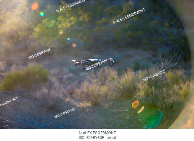 Drone (unmanned aerial vehicle) flying mid air over arid landscape