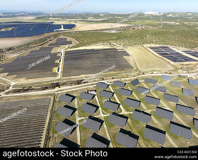 Rows of solar panels at a photovoltaic plant and the town of Espejo in the background. Aerial view. Drone shot. Córdoba province, Andalucía, Spain