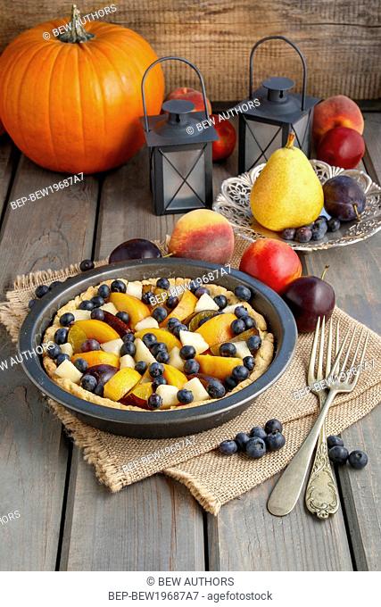 Tart with peach, pumpkin, plum, pear and blueberry in autumn setting. Party dessert