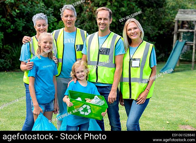 Portrait of caucasian multi generation male and female volunteer group collecting rubbish in field