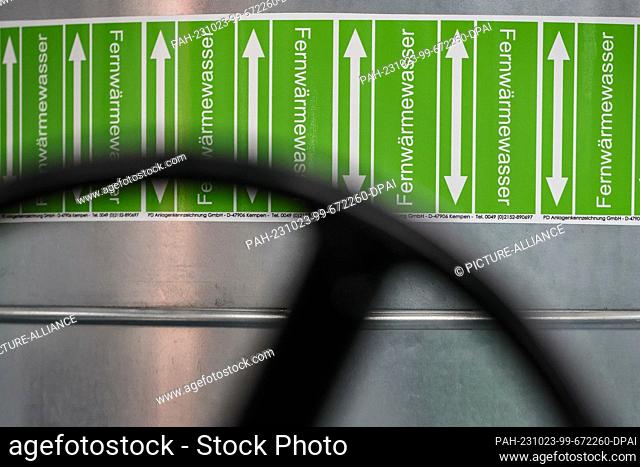 23 October 2023, Saxony, Leipzig: Stickers with ""district heating water"" are stuck on a pipe in the pump hall of the new combined heat and power plant South