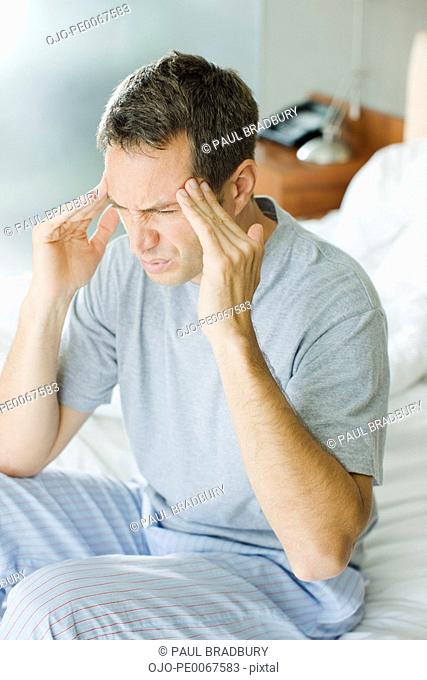 Man with headache rubbing forehead