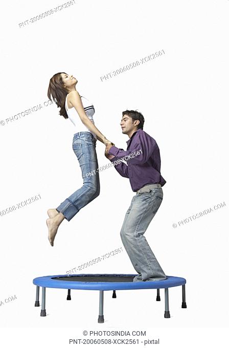 Side profile of a young man and a young woman jumping on a trampoline