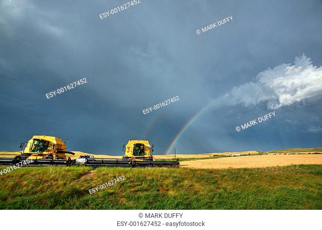 Rainbow behind parked combines in Saskatchewan