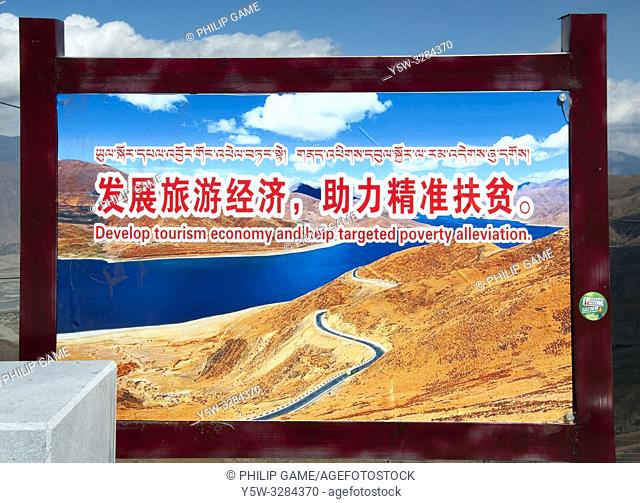 'Develop Tourism and Create Jobs' propaganda message displayed at a pass above Yamdrok Tso, a scenic lake west of Lhasa, Tibet, China