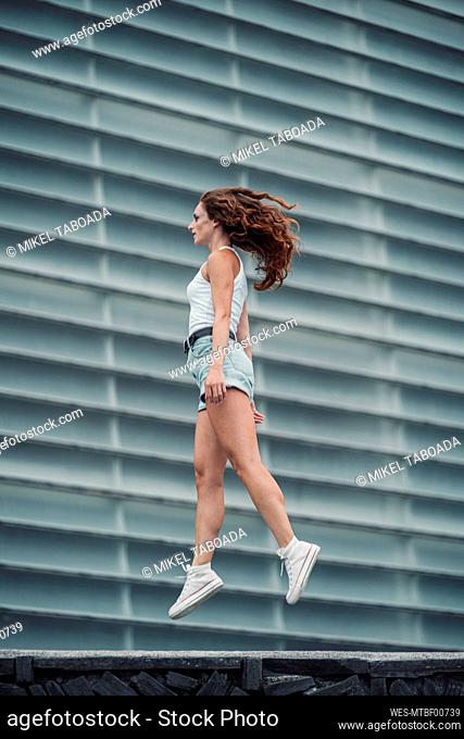 Young woman walking against wall