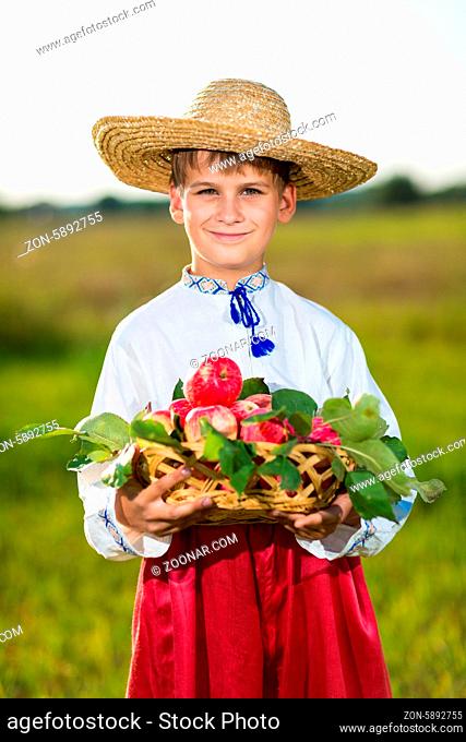 Happy boy hold Organic Apples in Autumn Garden.Healthy Food.Outdoors.Park. Basket of Apples.Harvest concept .Smiling farmer