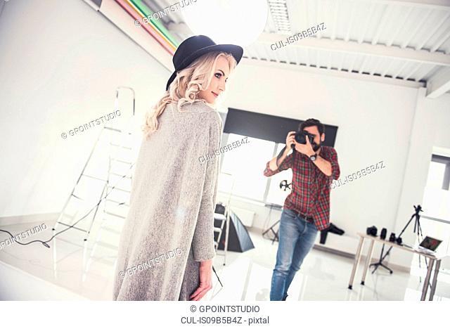 Male photographer photographing female model on studio white background