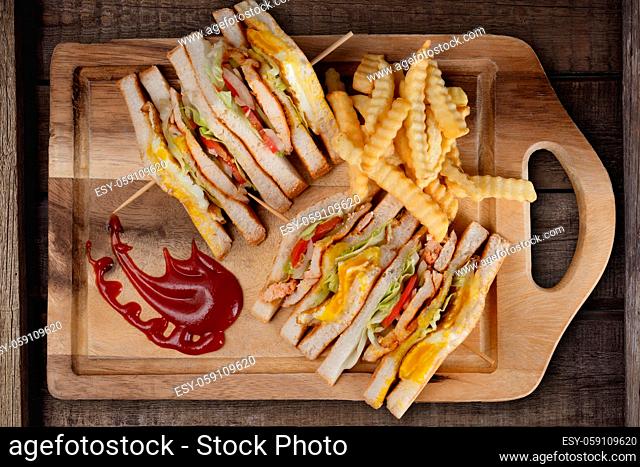 Top view of chicken club sandwiches and french fries isolated on rustic wooden table