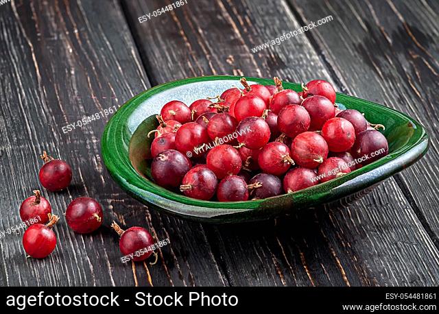 Red gooseberries on a dark table in a clay bowl