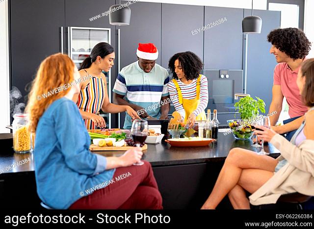 Happy diverse friends with santa hat cooking at christmas