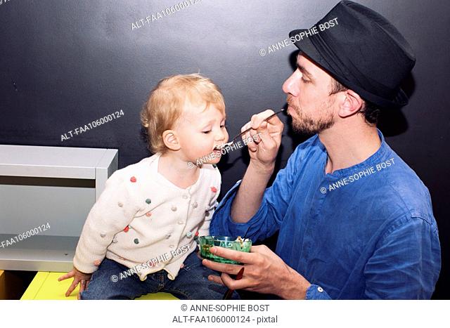 Father spoon feeding toddler