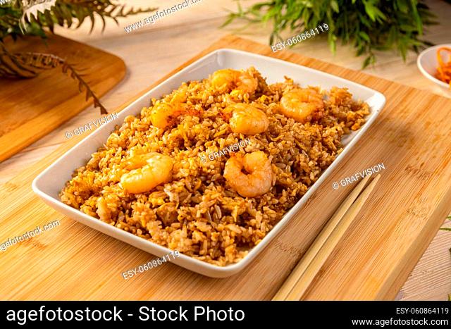 Fried rice with shrimp on the white dish on bamboo board