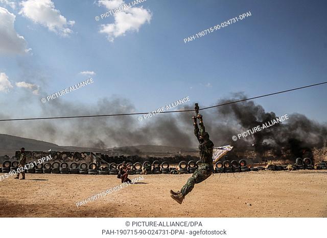 15 July 2019, Syria, Idlib: Fighters of Jaysh al-Izza formation of the Syrian armed opposition, take part in a military show during their graduation from a...