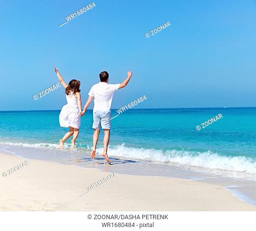 Young happy couple jumping on the beach