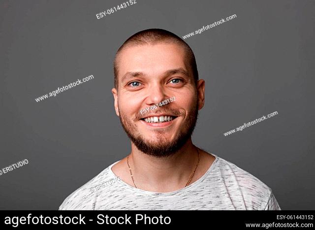 portrait of young smiling man on gray background