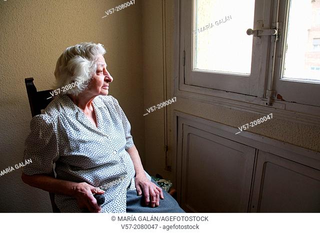 Portrait of elderly woman at home, sitting by the window