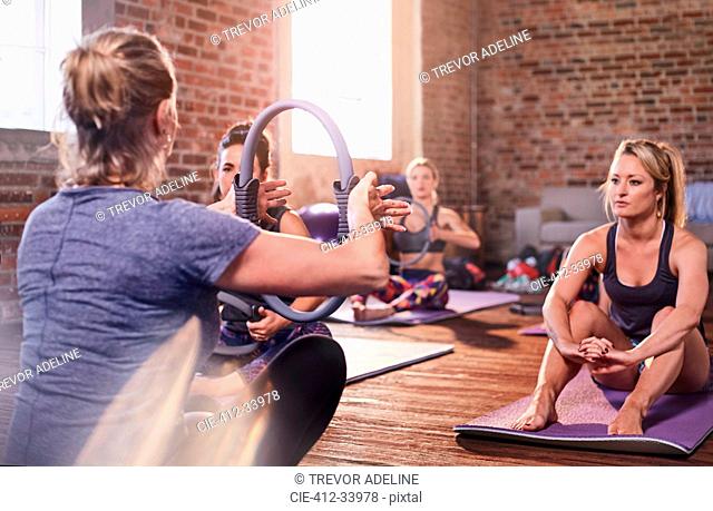 Fitness instructor explaining pilates ring to exercise class in gym studio