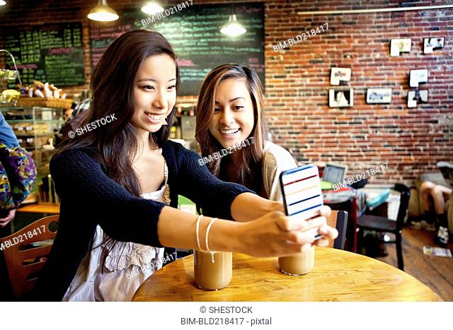 Women taking selfie with cell phone at cafe table